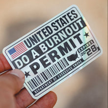 Sticker with text 'United States Do a Burnout Permit' held by a hand against a blurred background