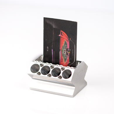An aluminum engine block business card holder with a custom laser cut farmtruck logo, containing a business card.