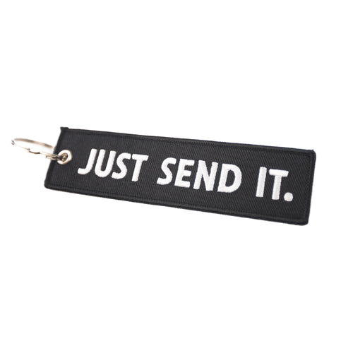 A black keychain with the text 'JUST SEND IT' in white embroidered stitching.