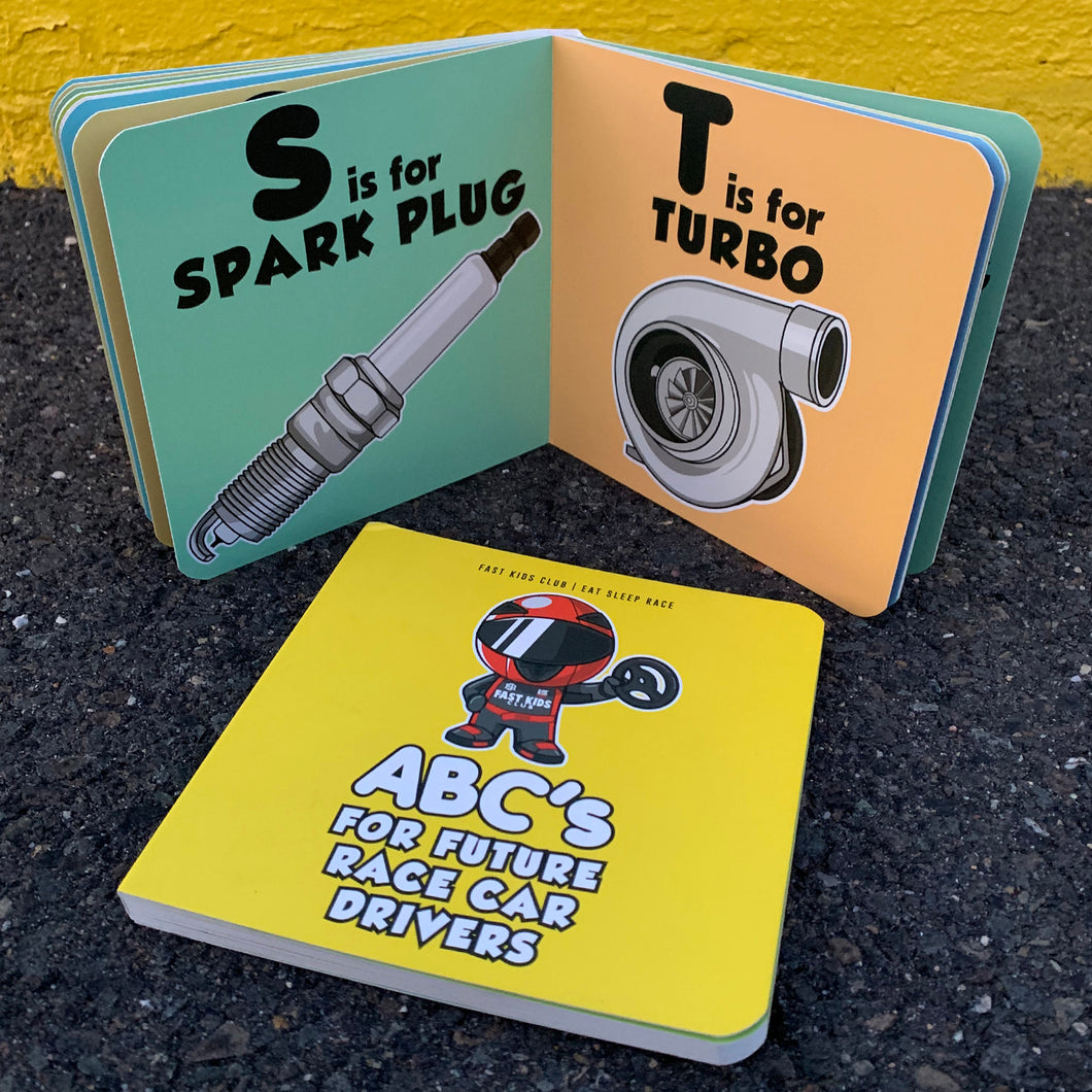 A board book with colorful pages, each illustrating a letter of the alphabet paired with a car-related word, such as 'S is for Spark Plug' and 'T is for Turbo'. The cover features a cartoon race car with the title 'ABC's for future race car drivers'.